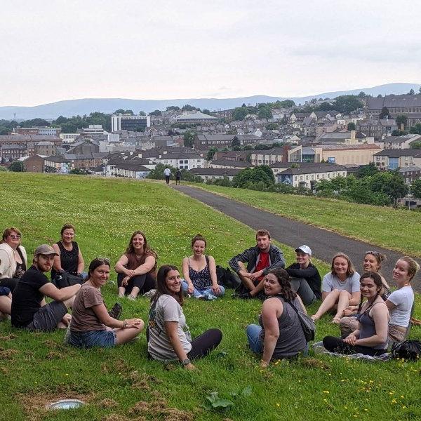 一群学生在小山上围坐成一圈，远处是北爱尔兰