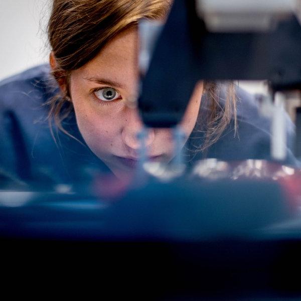 An engineering student's eye looks intently at a piece of equipment.